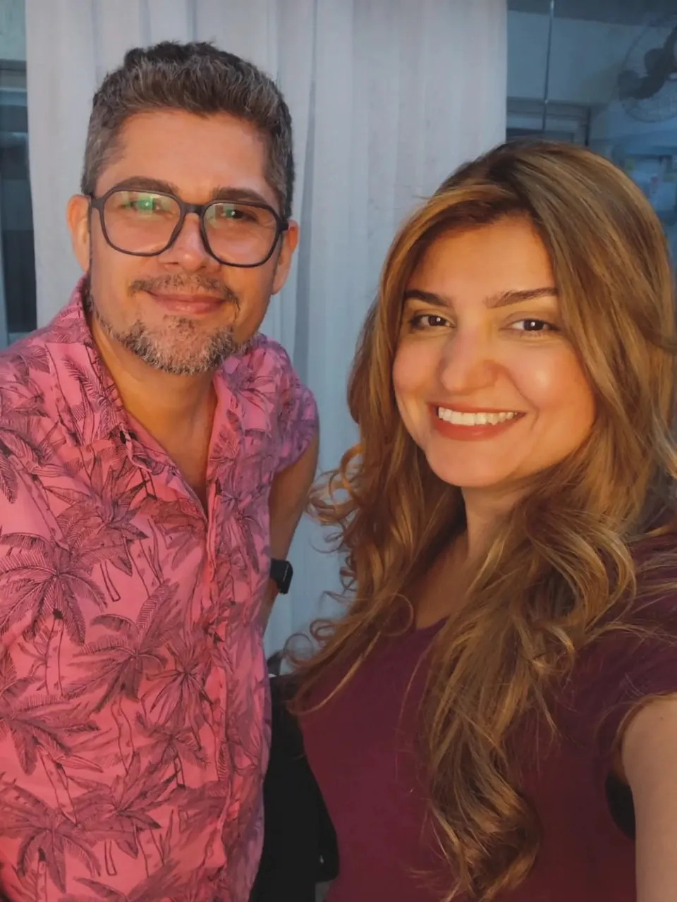 Pablo e uma cliente de cabelo acobreado longo sorriem juntos numa selfie no estúdio