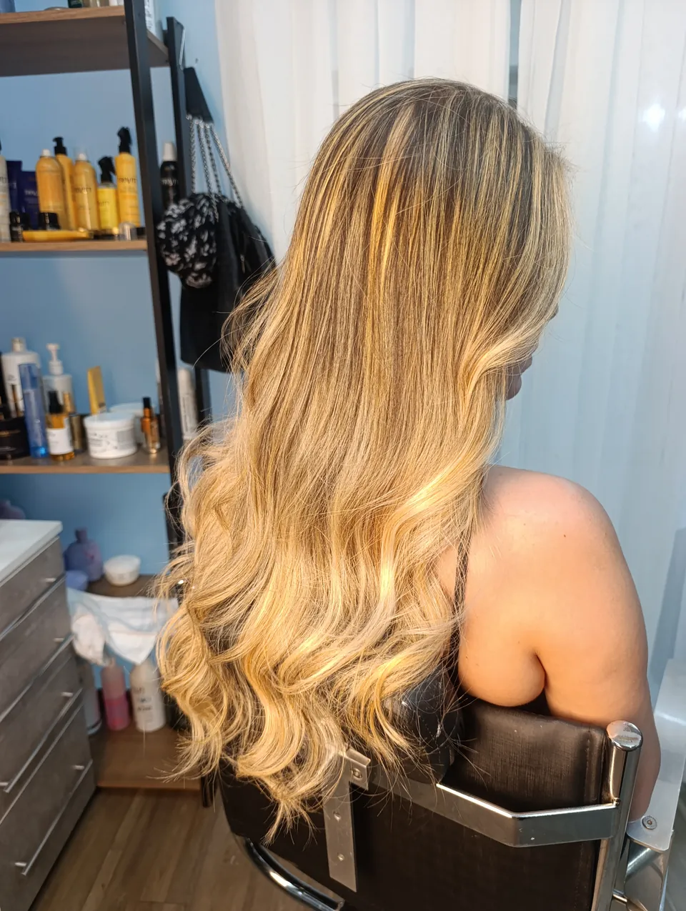 Balayage loiro longo e ondulado, de costas na cadeira do estúdio