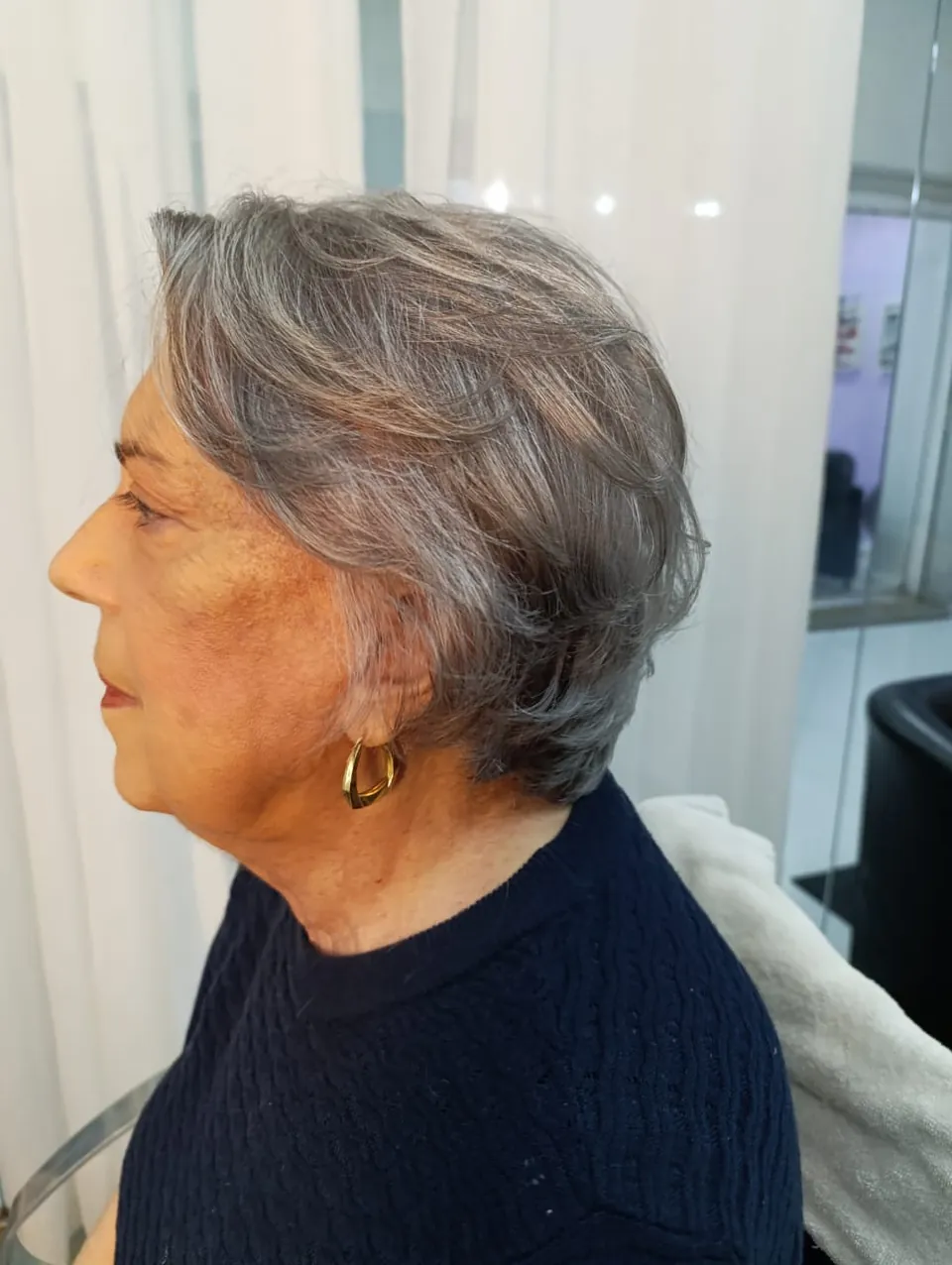 Cliente de perfil com cabelos grisalhos naturais em corte curto com volume
