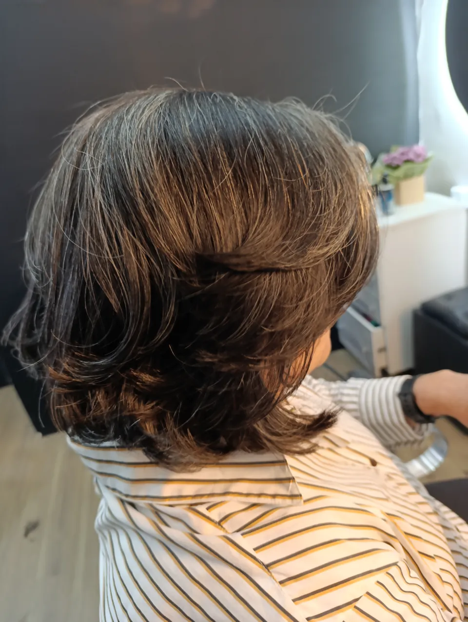 Corte bob em camadas castanho escuro com fios brancos e pontas iluminadas, de costas