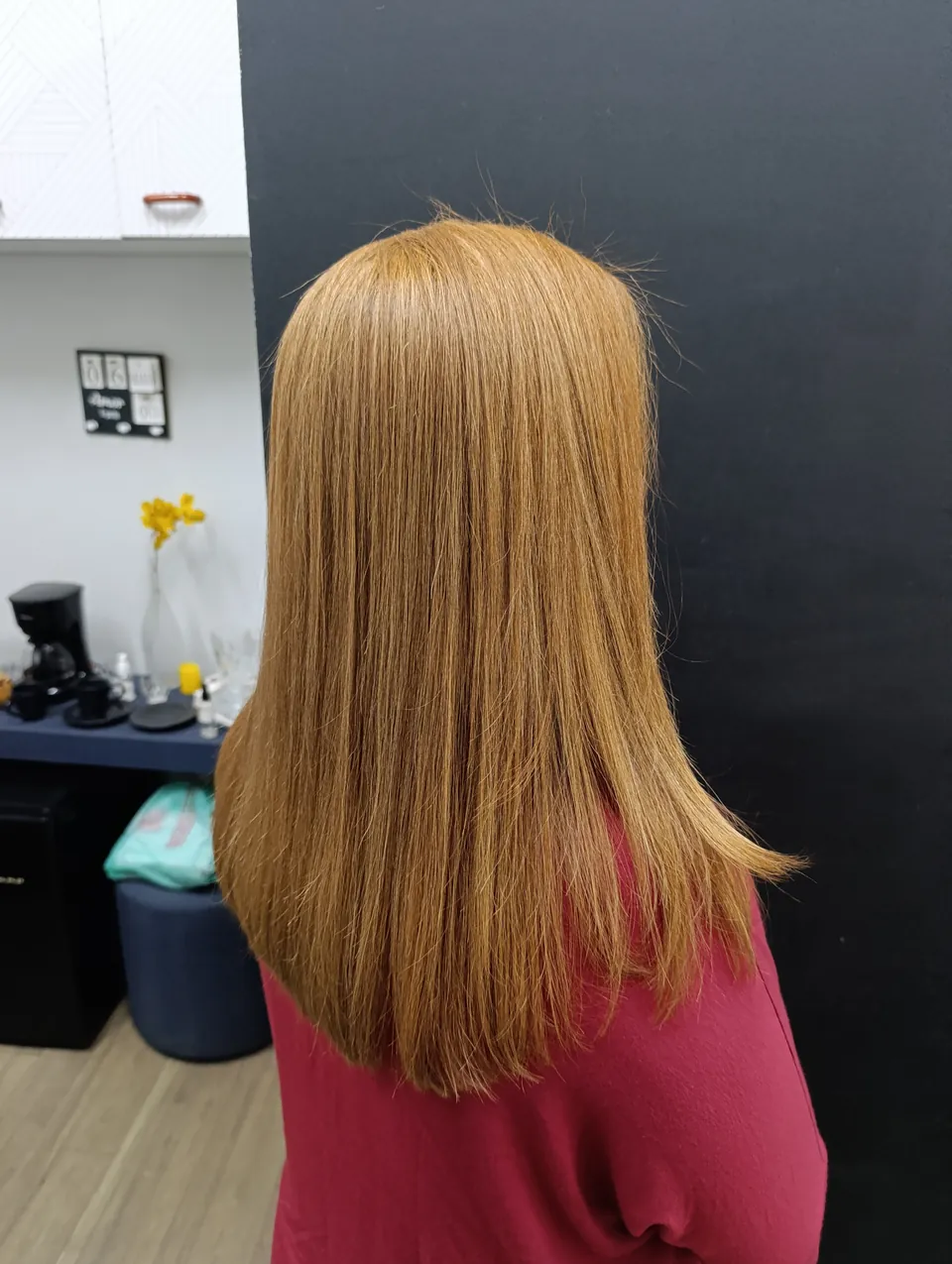 Cabelo longo e liso em tom dourado acobreado, de três quartos de costas