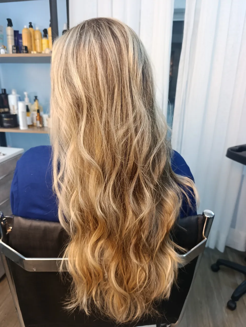 Mechas loiras longas e onduladas, de costas na cadeira do estúdio